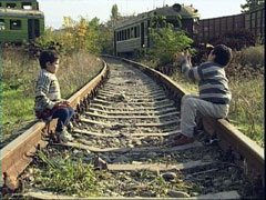 Two boys sitting on the railroad tracks