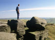 A young man standing on a gritstone outcrop at the southern edge of Kinder Scout in the Peak District