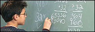 Boy writing on blackboard for Shares4Schools story