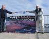 The two activists raise a banner at the roof of the hotel Hafnia in front of the parliament of Faroe (WDSF/ProWal)