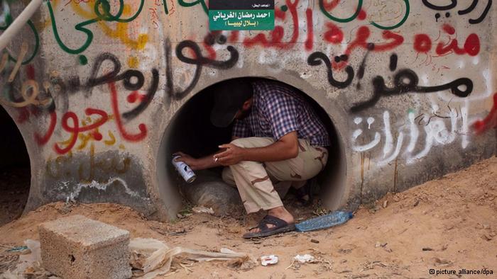 epa02975684 A Libyan rebel fighter paints on the wall of one of the pipes where Muammar Gaddafi allegedly found hiding, in Sirte, Libya, 21 October 2011. Libyan deposed leader Muammar Gaddafi was arrested on 20 October, some witnesses said he was found hiding in a drainage pipe in Sirte. He died later, along with his son Motassim. EPA/GUILLEM VALLE +++(c) dpa - Bildfunk+++
