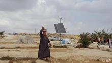 A Palestinian woman carries a bucket on her head as she passes a solar panel, in the West Bank village of Susya near Hebron, Wednesday, Oct. 7, 2009. Residents of a West Bank village bereft of electricity have been lifted out of the dark ages by an unlikely aid: a group of Israelis who installed solar panels and wind turbines to illuminate their makeshift homes. (AP Photo/Nasser Shiyoukhi)