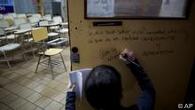 Eine Studentin schreibt einen Slogan auf eine Tür an der Universität, die den Blick in einen leeren Klassenraum freigibt (Foto: ddp images/AP Photo/Natacha Pisarenko)