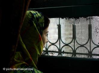 A woman looks through a barred window