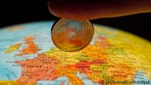 Ein Finger hält eine Ein-Euro-Münze über Europa (Foto: DPA)