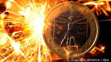Funken einer Wunderkerze fliegen über einer Euro-Münze aus Italien (Foto: dpa)