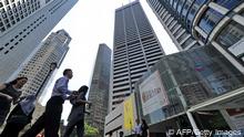 Menschen stehen vor mehreren Hochhäusern in Singapur (Bild: AFP)