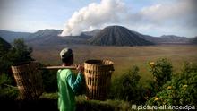 A farmer watches Mount Bromo spews hot clouds from Ngadisari Village, Probolinggo, Indonesia 