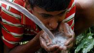 A boy quenches his thirst from a water hose at Durga Bari tea garden near Agartala, India