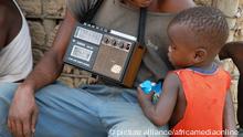 An African child listening to an old radio