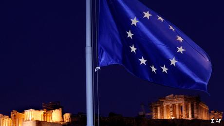 The EU flag flutters in the wind with the ancient Parthenon temple, right