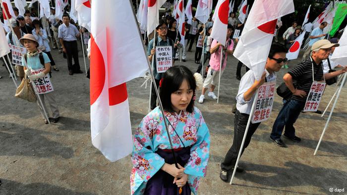 A kimono-clad protester, holding a Japanese flag, takes part in a rally, opposing China's territorial claim over the disputed islands, called Senkaku in Japan and Diaoyu in China, at a park in Tokyo, Saturday, Sept. 22, 2012. (AP Photo/Itsuo Inouye)