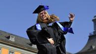 A woman celebrates graduation by jumping in the air