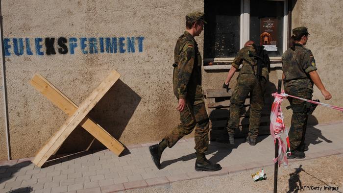 German troops serving in the NATO-led peacekeeping mission (KFOR) in Kosovo pass by a graffiti depicting EU Rule Of Law Mission in Kosovo (EULEX) in the town of Mitrovica on September 28, 2011. AFP PHOTO/ARMEND NIMANI (Photo credit should read ARMEND NIMANI/AFP/Getty Images) 