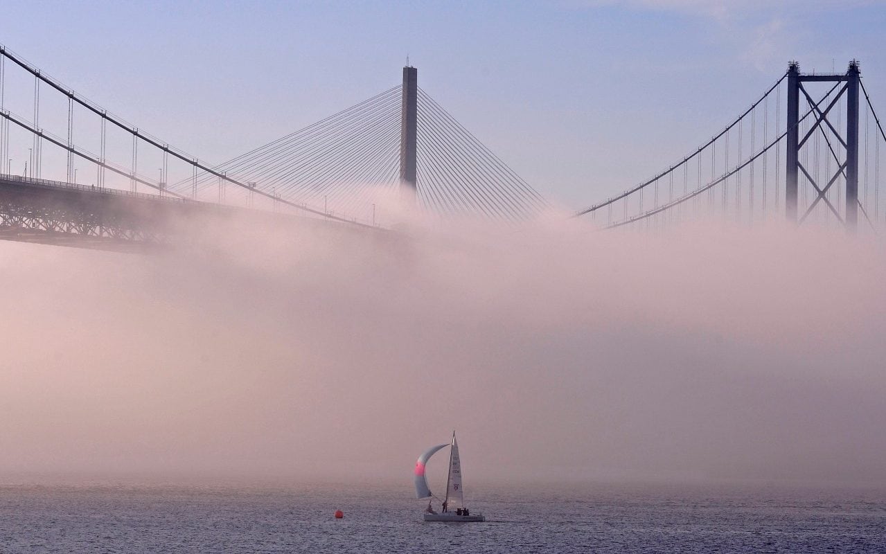 The towers of the Queensferry Crossing (C) and Forth Road Bridge (R) rise out of the mist enveloping the road decks